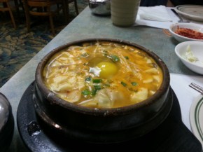 Korea soft tofu with dumplings. There's a cracked egg in the middle. The soup base was not thick. Simple flavor.